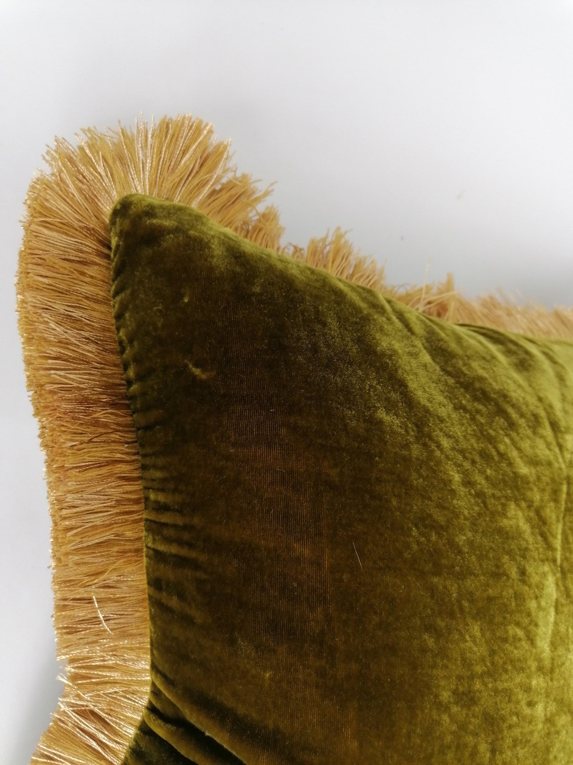 top corner of a pillow made of Chartreuse silk velvet with gold fringed trim 